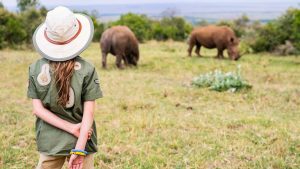 Girl on safari trip to tanzania standing watching rhinos